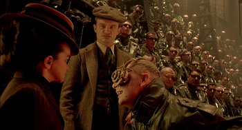 Movie still from “The City of Lost Children” (1995), directed by Jean-Pierre Jeunet – A group of men and a woman standing next to each other; Close Up shot, Over the shoulder angle
