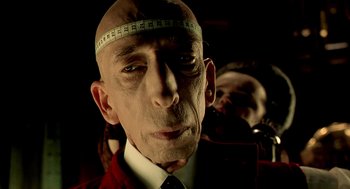 Movie still from “The City of Lost Children” (1995), directed by Jean-Pierre Jeunet – A man with a tape measure on his head; Close Up shot, Low angle