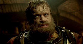 Movie still from “The City of Lost Children” (1995), directed by Jean-Pierre Jeunet – A man with a beard and a helmet on; Close Up shot, Low angle