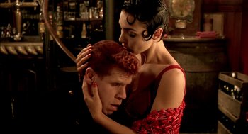 Movie still from “The City of Lost Children” (1995), directed by Jean-Pierre Jeunet – A man and a woman embracing each other in front of a bar; Close Up shot, Low angle