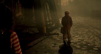 Movie still from “The City of Lost Children” (1995), directed by Jean-Pierre Jeunet – A person walking down a street in the fog; Wide shot, High angle
