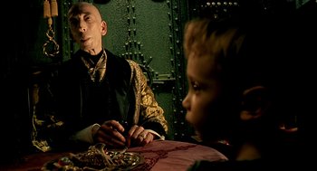 Movie still from “The City of Lost Children” (1995), directed by Jean-Pierre Jeunet – An older man sitting at a table with a young boy; Medium shot, Over the shoulder angle