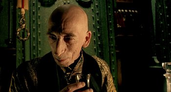 Movie still from “The City of Lost Children” (1995), directed by Jean-Pierre Jeunet – An old man with a bald head holding a glass; Close Up shot, High angle