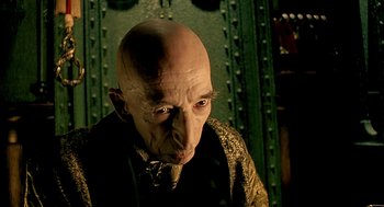 Movie still from “The City of Lost Children” (1995), directed by Jean-Pierre Jeunet – An old man with a bald head wearing a bow tie; Close Up shot, Low angle