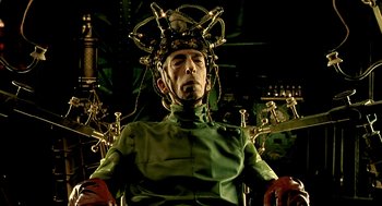 Movie still from “The City of Lost Children” (1995), directed by Jean-Pierre Jeunet – A man in a green suit with a metal head piece; Close Up shot, Low angle