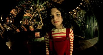 Movie still from “The City of Lost Children” (1995), directed by Jean-Pierre Jeunet – A young girl in a striped shirt and red overalls; Medium shot, High angle