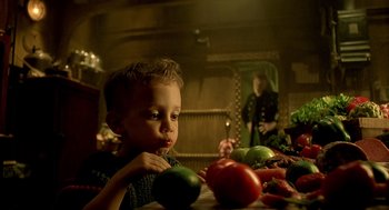 Movie still from “The City of Lost Children” (1995), directed by Jean-Pierre Jeunet – A young boy sitting in front of a bunch of vegetables; Close Up shot, Over the shoulder angle