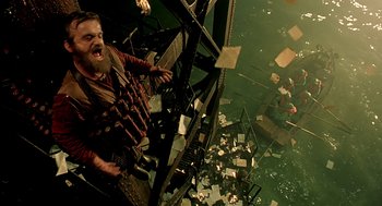 Movie still from “The City of Lost Children” (1995), directed by Jean-Pierre Jeunet – A man with a bunch of papers in his mouth; Medium shot, Overhead angle