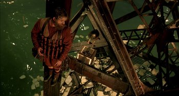 Movie still from “The City of Lost Children” (1995), directed by Jean-Pierre Jeunet – A man with a bunch of guns strapped to his chest; Wide shot, Overhead angle