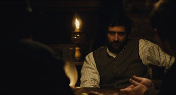 Movie still from “The Cobbler” (2014), directed by Tom McCarthy – A man sitting at a wooden table in front of a lit candle; Medium shot, Over the shoulder angle
