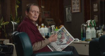 Movie still from “The Cobbler” (2014), directed by Tom McCarthy – A man sitting in a chair holding up a newspaper; Close Up shot, Over the shoulder angle