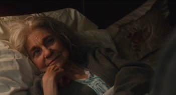 Movie still from “The Cobbler” (2014), directed by Tom McCarthy – An older woman laying in bed with her hand under her chin; Close Up shot, Over the shoulder angle