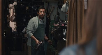 Movie still from “The Cobbler” (2014), directed by Tom McCarthy – A man standing in front of a mirror in a workshop; Medium shot, Over the shoulder angle