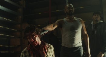 Movie still from “The Cobbler” (2014), directed by Tom McCarthy – A man is cutting another man's head with a large knife; Medium shot, Over the shoulder angle