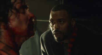 Movie still from “The Cobbler” (2014), directed by Tom McCarthy – A man in a suit stares at another man in a suit with blood on his face; Close Up shot, Over the shoulder angle