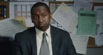 Movie still from “The Cobbler” (2014), directed by Tom McCarthy – A man wearing a suit and tie in front of papers; Close Up shot, Over the shoulder angle