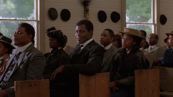 Movie still from “The Color Purple” (1985), directed by Steven Spielberg – A group of people sitting in a row of pews; Medium shot, Low angle