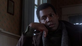 Movie still from “The Color Purple” (1985), directed by Steven Spielberg – A man sitting in front of a window with his hand under his chin; Close Up shot, Low angle