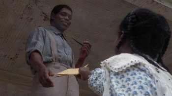 Movie still from “The Color Purple” (1985), directed by Steven Spielberg – A man and a woman are holding a piece of paper; Medium shot, Over the shoulder angle
