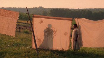 Movie still from “The Color Purple” (1985), directed by Steven Spielberg – A man standing in a field next to a tent; Extreme Wide shot, Low angle
