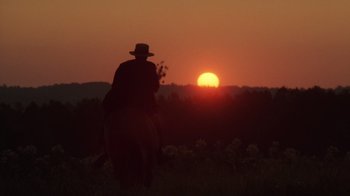 Movie still from “The Color Purple” (1985), directed by Steven Spielberg – A man riding a horse in a field at sunset; Wide shot, Low angle
