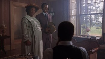 Movie still from “The Color Purple” (1985), directed by Steven Spielberg – A man and a woman standing next to each other in a room; Medium shot, Over the shoulder angle