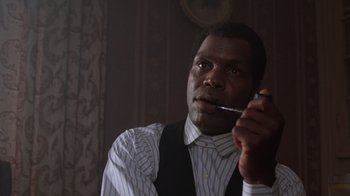 Movie still from “The Color Purple” (1985), directed by Steven Spielberg – A black man smoking a cigarette while wearing a suit; Close Up shot, Low angle