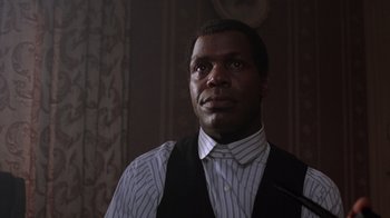 Movie still from “The Color Purple” (1985), directed by Steven Spielberg – A man wearing a vest and a striped shirt; Close Up shot, Low angle