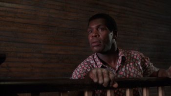 Movie still from “The Color Purple” (1985), directed by Steven Spielberg – A man with a cell phone leaning on a railing; Close Up shot, Low angle
