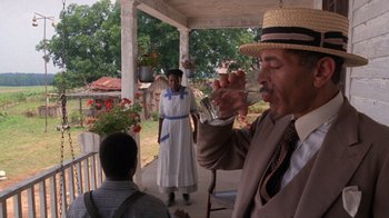 Movie still from “The Color Purple” (1985), directed by Steven Spielberg – A man and a woman are drinking from a cup; Medium shot, Low angle