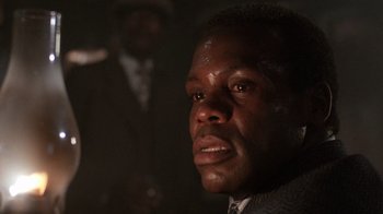 Movie still from “The Color Purple” (1985), directed by Steven Spielberg – A person wearing a suit and tie; Close Up shot, Low angle