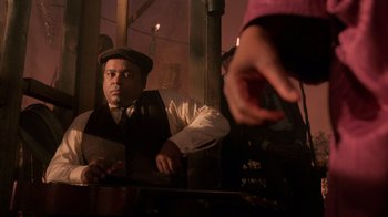 Movie still from “The Color Purple” (1985), directed by Steven Spielberg – A man sitting at a table in front of another man; Medium shot, Low angle