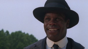 Movie still from “The Color Purple” (1985), directed by Steven Spielberg – A person wearing a suit and a hat; Close Up shot, Low angle