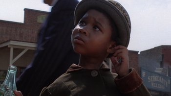 Movie still from “The Color Purple” (1985), directed by Steven Spielberg – A little boy wearing a hat while holding his hand to his ear; Close Up shot, Low angle
