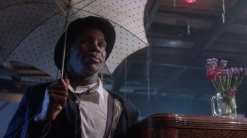 Movie still from “The Color Purple” (1985), directed by Steven Spielberg – A man holding an open umbrella in the rain; Close Up shot, Low angle