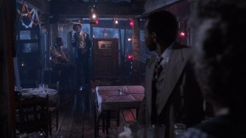 Movie still from “The Color Purple” (1985), directed by Steven Spielberg – A man standing in a room next to a table; Wide shot, Over the shoulder angle