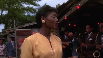 Movie still from “The Color Purple” (1985), directed by Steven Spielberg – A woman in a yellow shirt is holding a saxophone; Medium shot, Low angle