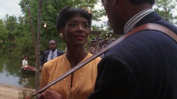 Movie still from “The Color Purple” (1985), directed by Steven Spielberg – An older woman in a yellow dress holding a cane; Close Up shot, Over the shoulder angle