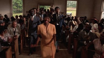 Movie still from “The Color Purple” (1985), directed by Steven Spielberg – A group of men and women in a room; Wide shot, Low angle