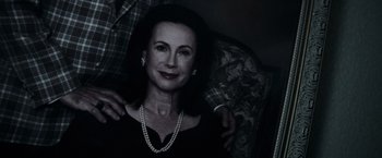 Movie still from “The Conjuring 2” (2016), directed by James Wan – An older woman wearing a necklace and pearls is sitting next to a man; Close Up shot, Low angle