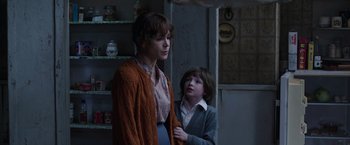 Movie still from “The Conjuring 2” (2016), directed by James Wan – A woman standing next to a boy in a room; Medium shot, Over the shoulder angle
