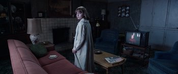 Movie still from “The Conjuring 2” (2016), directed by James Wan – A woman standing in a living room in a robe; Wide shot, High angle