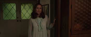 Movie still from “The Conjuring 2” (2016), directed by James Wan – A woman standing in front of a door wearing a white dress; Medium shot, Over the shoulder angle