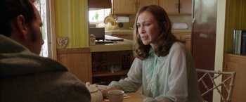 Movie still from “The Conjuring 2” (2016), directed by James Wan – A woman sitting at a table with a cup of coffee; Medium shot, Over the shoulder angle