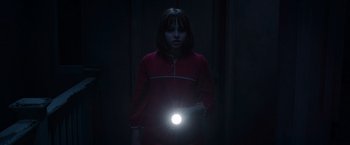 Movie still from “The Conjuring 2” (2016), directed by James Wan – A woman holding a flashlight in a dark room; Medium shot, High angle