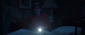 Movie still from “The Conjuring 2” (2016), directed by James Wan – A young girl in a red jacket is holding a flashlight; Medium shot, High angle