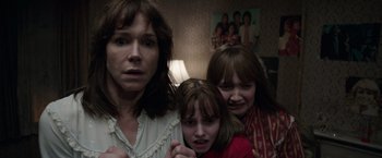 Movie still from “The Conjuring 2” (2016), directed by James Wan – A woman and two young girls in front of a lamp; Medium shot, Over the shoulder angle