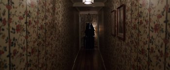 Movie still from “The Conjuring 2” (2016), directed by James Wan – A woman dressed as a nun in a dark hallway; Wide shot, Over the shoulder angle