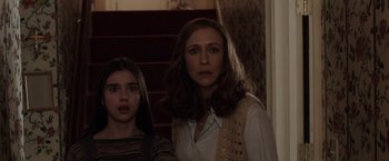 Movie still from “The Conjuring 2” (2016), directed by James Wan – Two women standing next to each other near a staircase; Medium shot, Over the shoulder angle