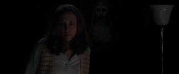 Movie still from “The Conjuring 2” (2016), directed by James Wan – A woman standing in front of an image of a nun; Medium shot, Over the shoulder angle